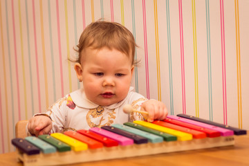 little girl playing on a colorful xylophone