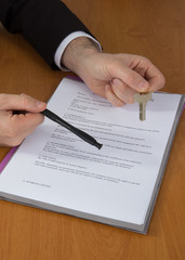 Cropped image of man signing contract with keys on it