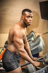 Fototapeta na wymiar Muscular black male bodybuilder exercising on treadmill in gym