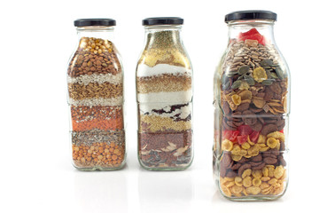 Decorative glass bottles with seeds isolated on white