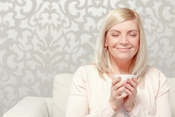 Woman drinks tea on the sofa