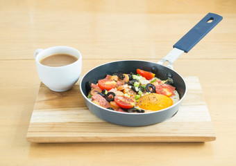 Fried egg with sausage in a pan and  hot coffee on wooden table