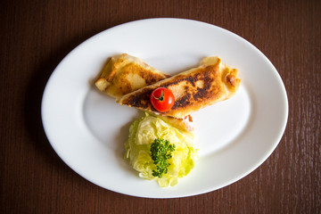Crepes with ham and cheese on wooden background