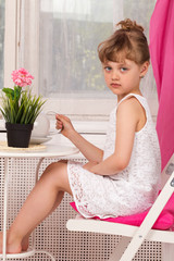 Little girl in a white dress on a pink background window curtain