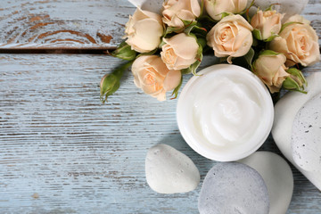 Cosmetic cream with flowers and spa stones on wooden background