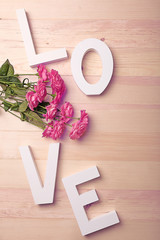Beautiful roses with word LOVE on wooden background
