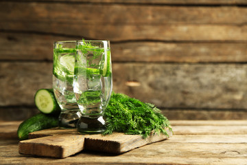 Glasses with fresh organic cucumber water on wooden table
