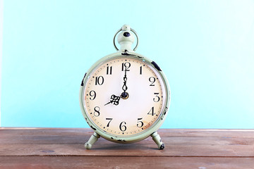 Alarm clock on wooden table on blue background