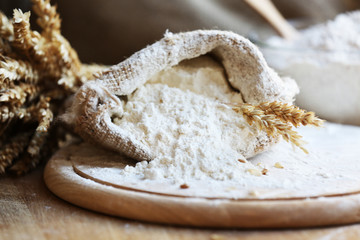 Flour in burlap bag on cutting board and wooden table