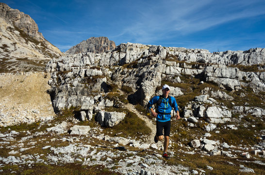 Man in blue jacket running on the trail