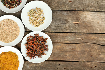 Different spices on plates, on old wooden table