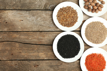 Different spices on plates, on old wooden table
