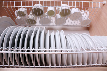 Clean dishes drying on metal dish rack on shelf