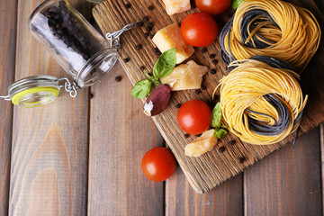 Raw pasta with cheese and vegetables on wooden background