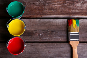 Metal buckets with colorful paint near brush