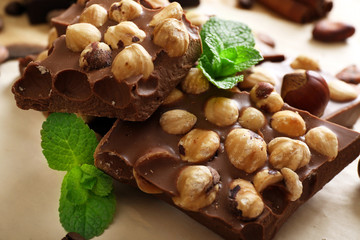 Chocolate with nuts, spices and mint on paper, closeup
