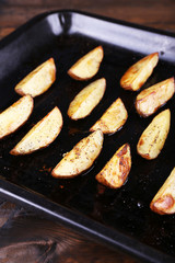 Baked potatoes with spices on pan on table close up