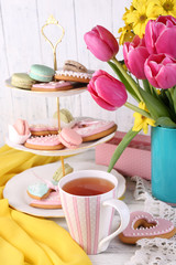 Composition of spring flowers, tea and cookies on table