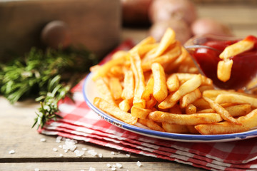 Tasty french fries on plate, on wooden table background