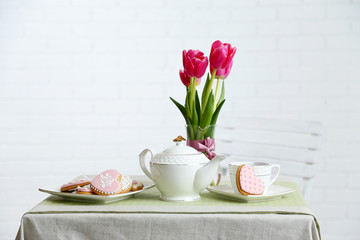 Tea set with flowers on table, on light background