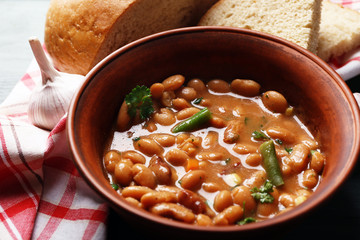 Bean soup in bowl on napkin, on wooden table background
