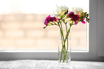 Beautiful spring flowers in glass vase on windowsill background