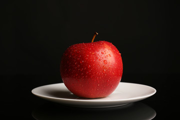 Apple on saucer on black background