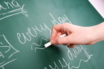 Teacher hand writing grammar sentences on blackboard background