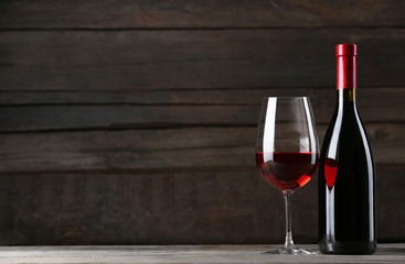 Wine bottle with glass on wooden background