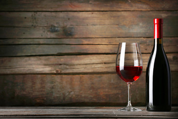 Wine bottle with glass on wooden background