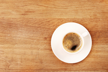 Cup of coffee on wooden table, top view