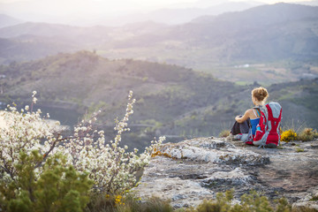 Woman tourist sitting on edge of rock