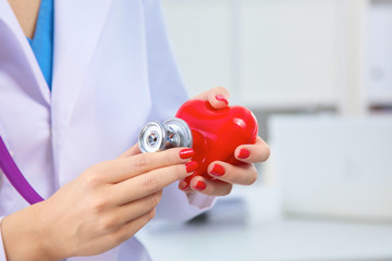 Doctor with stethoscope examining red heart