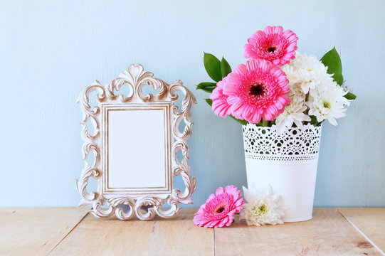 summer bouquet of flowers and victorian frame on the wooden tabl