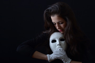 a brunette girl holding a white theatrical mask