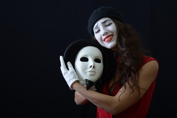 the girl is MIME holding a white mask and smiles