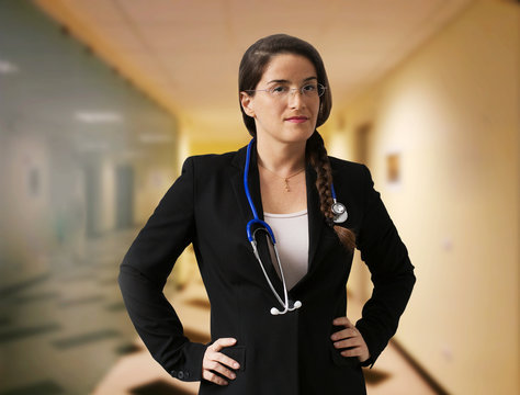 FEMALE DOCTOR WITH STETHOSCOPE AND GLASS INTO HOSPITAL CORRIDOR
