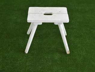 Small white wooden chair standing on green background