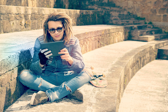handsome guy with dreadlocks readng a tablet warm filter applied