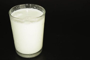 Milk in a glass on a black background.