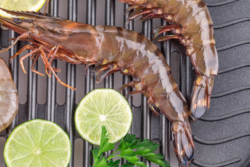 Raw shrimps on pan with lemon.