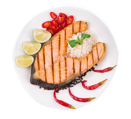 Grilled salmon steak with vegetables on plate.