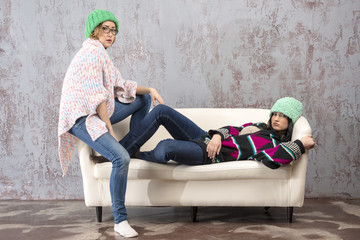 Obraz premium Two Young cheerful girl in a woolen hat in sofa