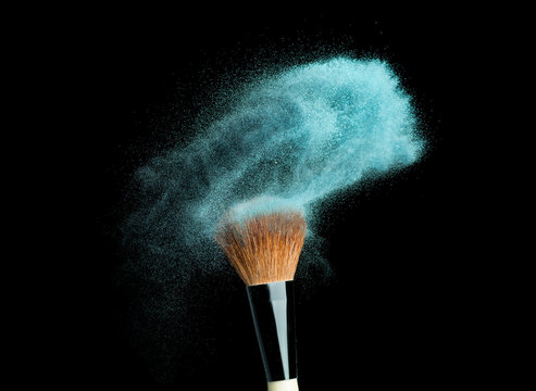 powder brush on black background with blue powder splash