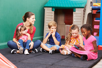 Gruppe Kinder mit Bilderbuch im Kindergarten
