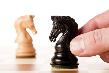 Hand putting a black chess piece on a table