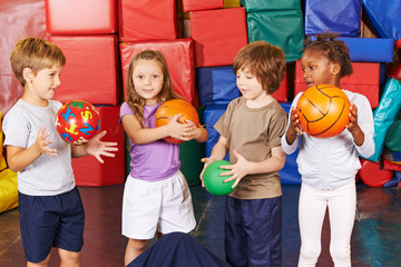 Kinder spielen mit Bällen in Turnhalle