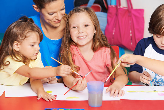 Lehrerin und Kinder malen in Vorschule