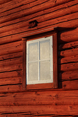 Old frosty window on old red Swedish cabin