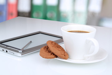 Close up image of cup of coffee with cookies. digital tablet on